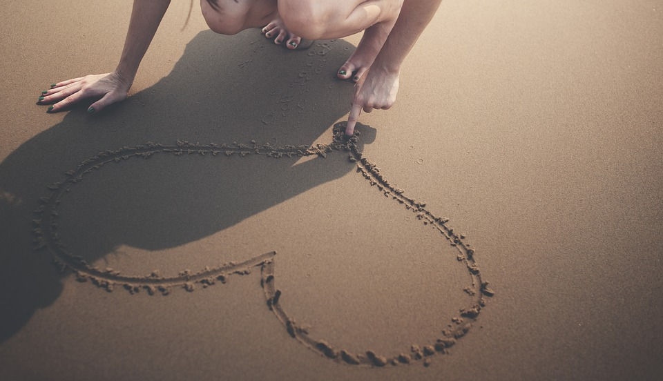 heart-drawn-in-sand-withindex-finger-loving-the-one-happy-island-ARUBA